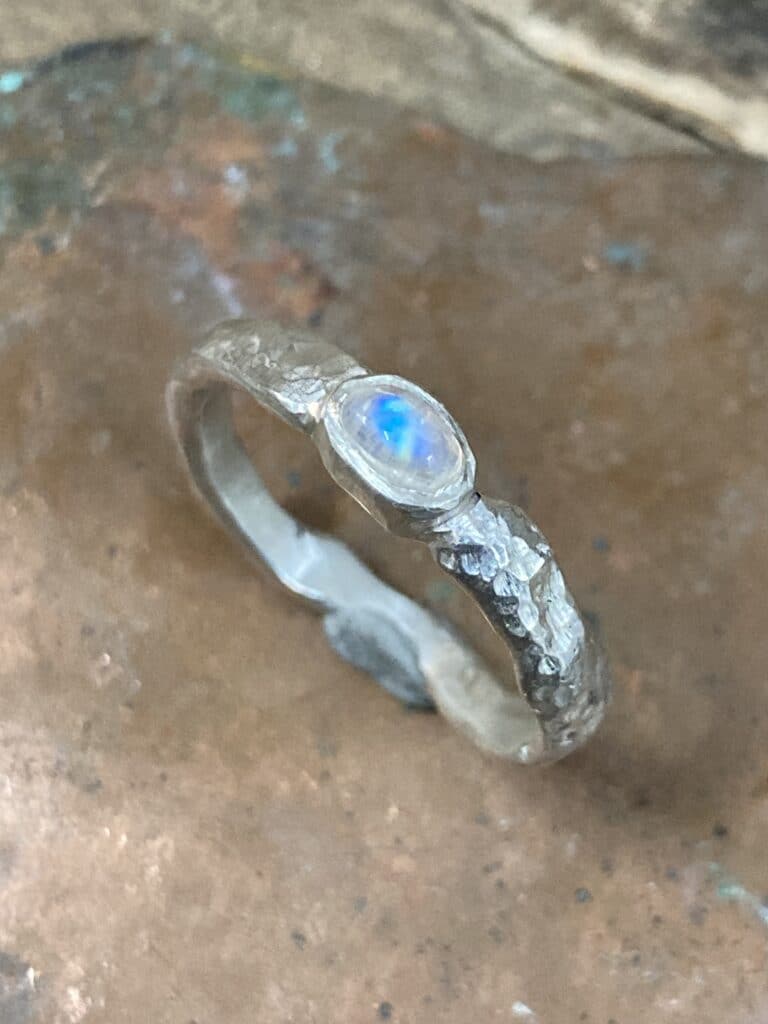 Bague en Pierre de Lune et Argent Martelé Style Bohème Bague artisanale en argent martelé sertie d'une pierre de lune aux reflets bleus, style bohème et texturé.