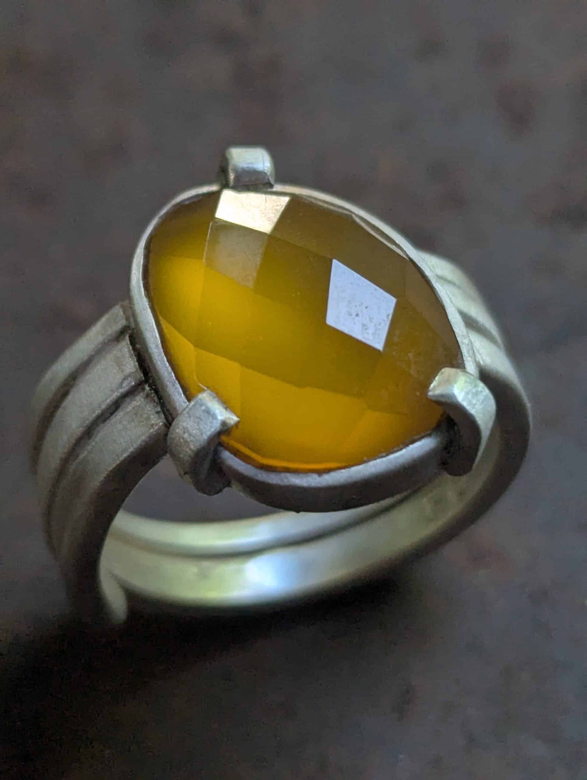 Bague en Argent avec Pierre Jaune Facettée – Style Moderne Bague en argent ornée d'une grande pierre jaune ovale facettée, montée sur un anneau large à trois branches.